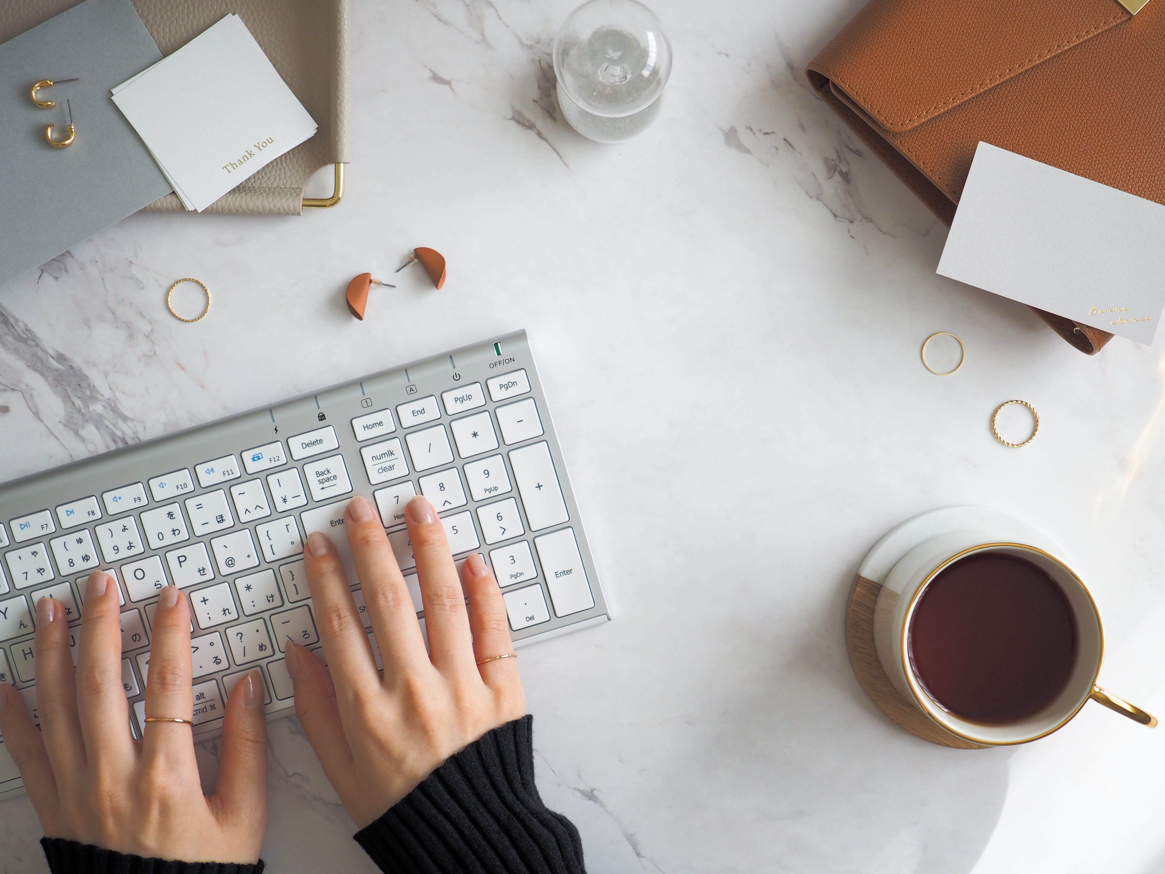 Tippen auf Tastatur mit Kaffee und Notizen, ideal für Beiträge zu Homeoffice und Produktivitätstipps.