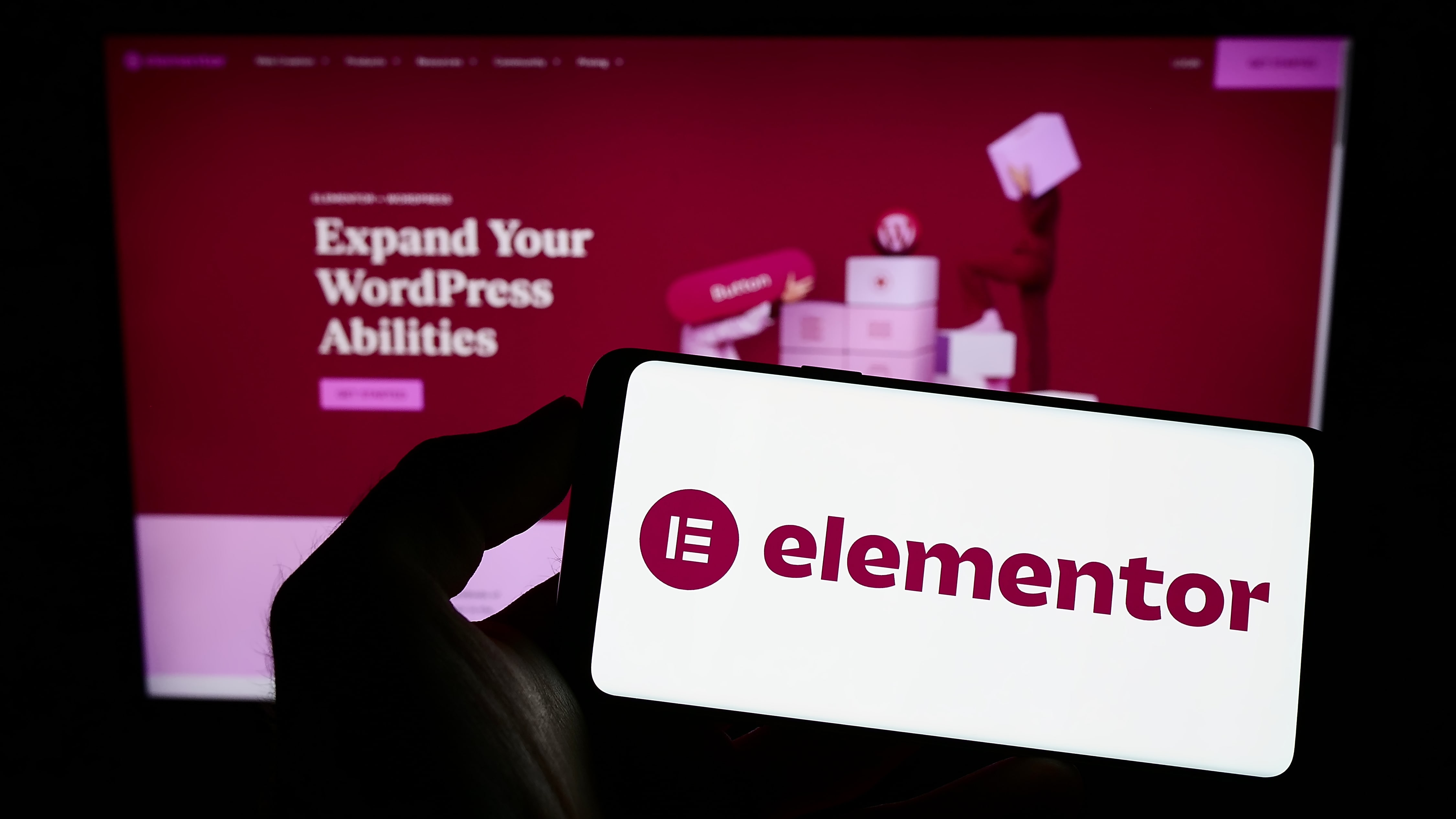 Smartphone mit Elementor-Logo vor einem Bildschirm, der das Thema WordPress-Fähigkeiten-Erweiterung zeigt.