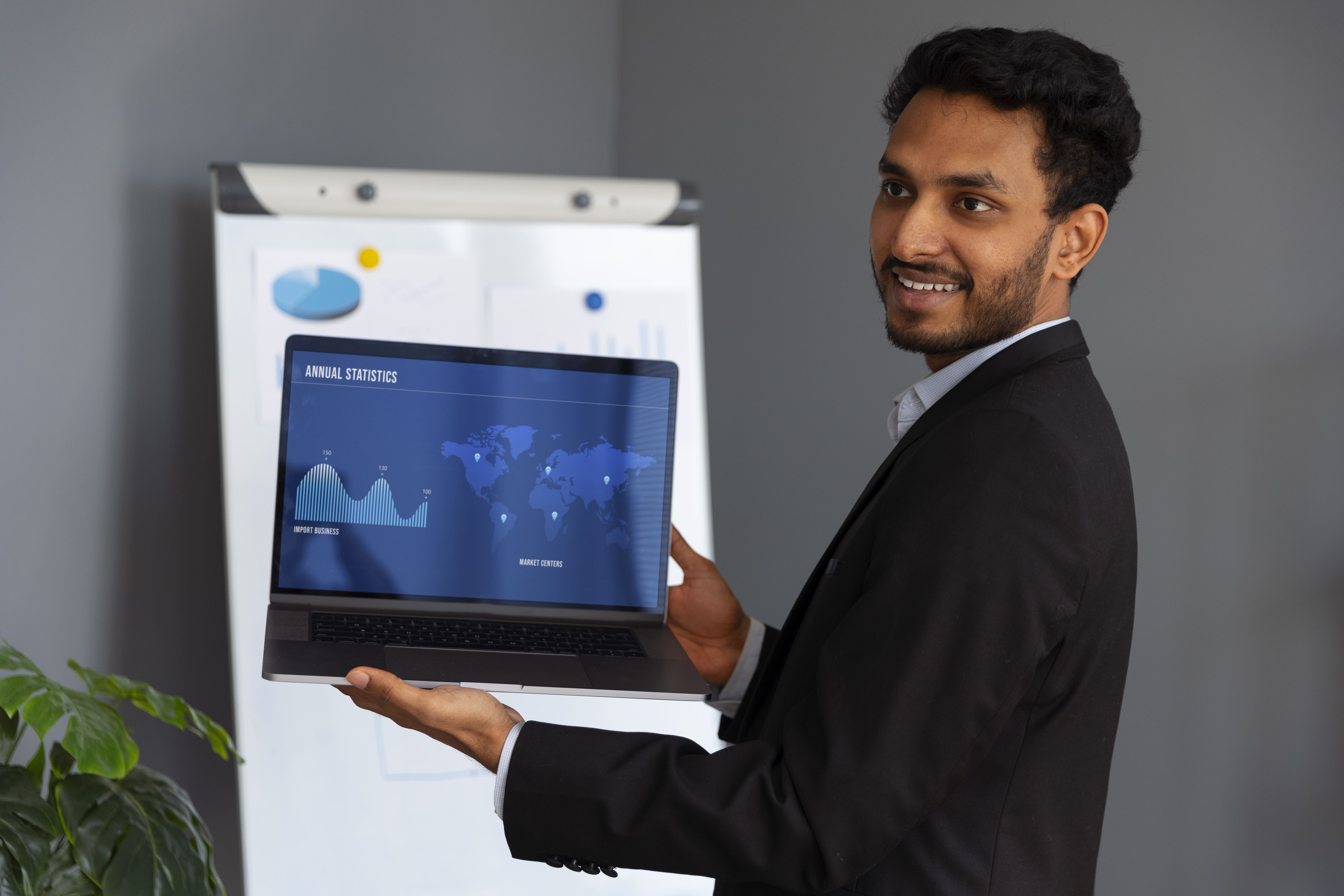 Geschäftsmann präsentiert Unternehmensstatistik auf Laptop bei Präsentation über globale Marktanalysen.